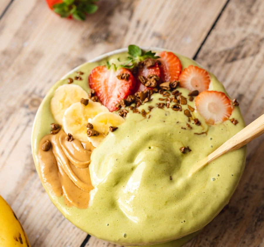 Green smoothie bowl with fruit on a wooden table