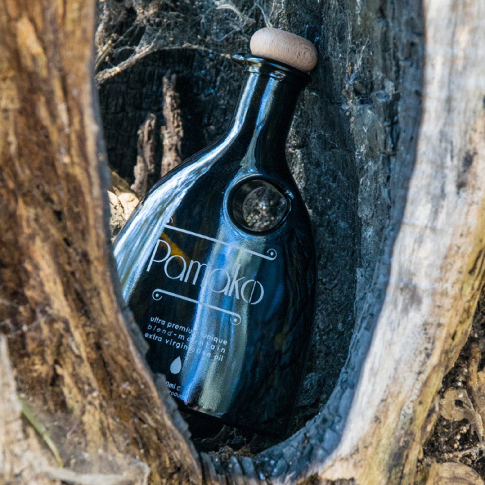 Elegant black murano bottle Pamako Blend EVOO in a wood.